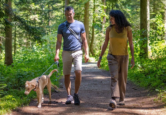 Couple walking their dog in a pet friendly hiking trail