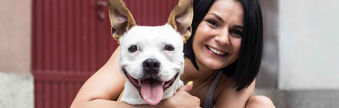 Young woman hugging her dog and laughing