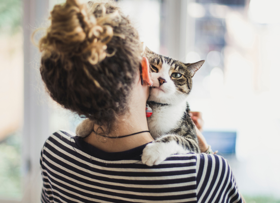 a woman facing forward touches cheeks with her cat